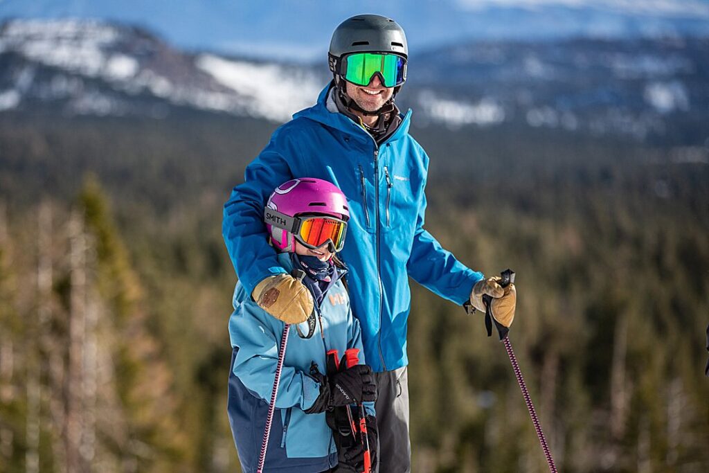 Parent and child dressed in ski clothes smiling